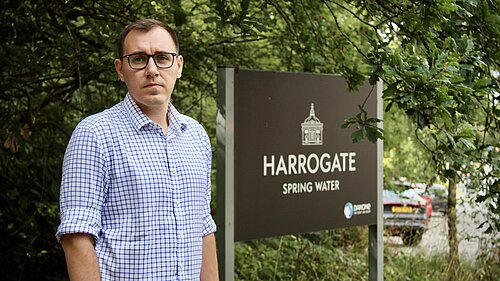 Tom Gordon MP standing next to Harrogate Spring Water sign
