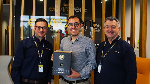 Tom Gordon MP, stood in the EnviroVent building, holding their 3 millionth fan with two employees 