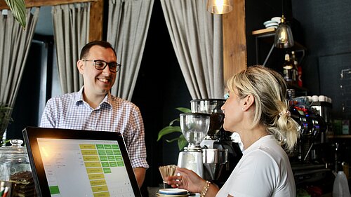 Tom Gordan MP speaking with cashier at cafe