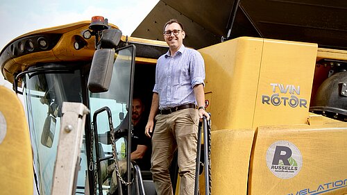 Tom Gordon MP stood on a combine harvester.