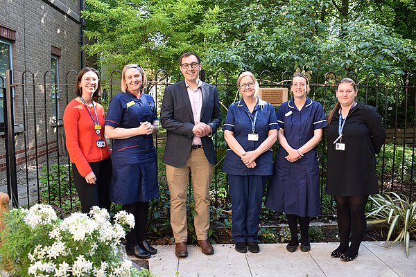 Tom Gordon stood in a courtyard at Harrogate Hospital with 5 charity and hospital employees