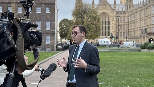 Tom Gordon stood speaking to the media outside the Houses of Parliament