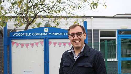 Tom Gordon MP standing in front of a primary school