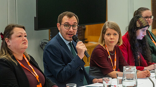 Tom Gordon talking into a mic at a table of people