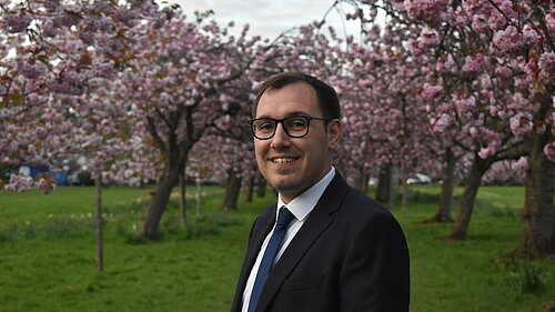 Tom stood in front of cherry blossoms