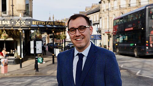 Tom Gordon stood in front of Bettys and a 36 bus in Harrogate