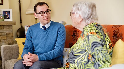 Tom Gordon sat on a sofa with a pensioner