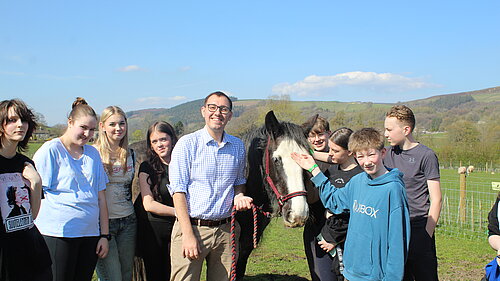 Tom Gordon MP stands in field with horse and group of young carers 