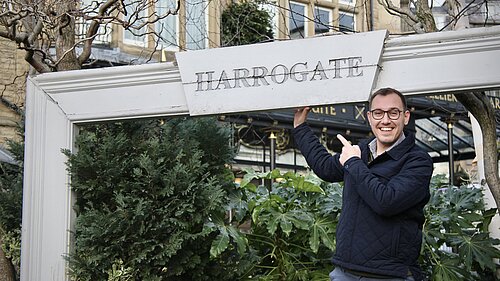 Tom Gordon MP under a sign saying Harrogate