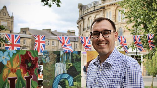 Tom Gordon MP stood in Central Harrogate with Union Jack Flags behind him