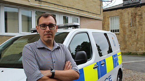 Tom Gordon MP in front of a police van with his arms folded