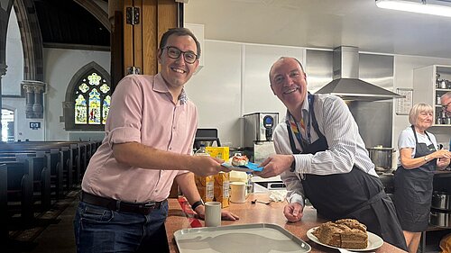 Tom Gordon with Harrogate Homeless Project CEO Richard Cooper at St Peter's Church in Harrogate, being passed a slice of cheescake