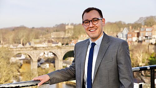 Tom standing in front of a backdrop of Knaresborough