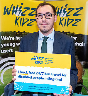 Tom Gordon MP holding a sign supporting Whizz Kids Charity
