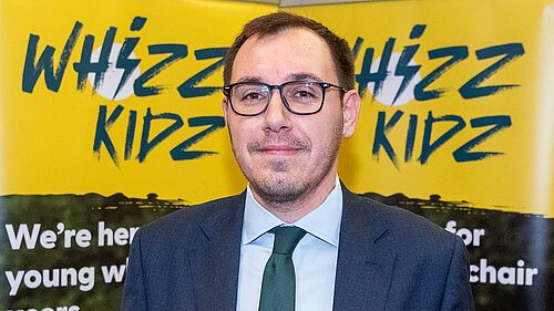 Tom Gordon MP holding a sign supporting Whizz Kids Charity