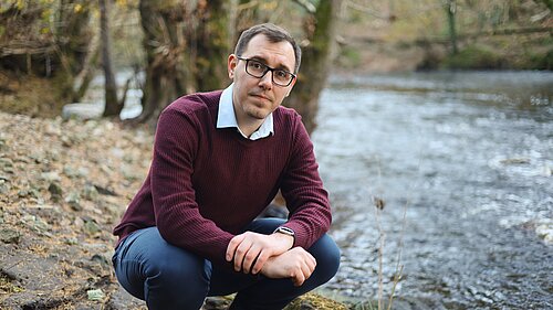 Tom Gordon MP crouching next to the River Nidd