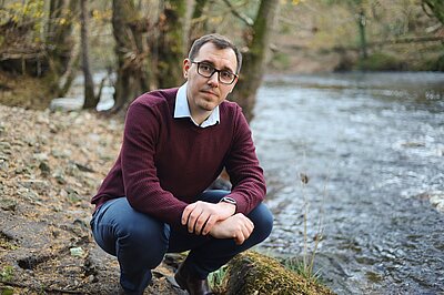 Tom Gordon MP crouched next to the River Nidd